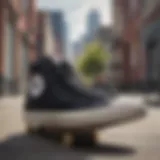 A pair of black high top Convers sneakers on a skateboard in a urban setting